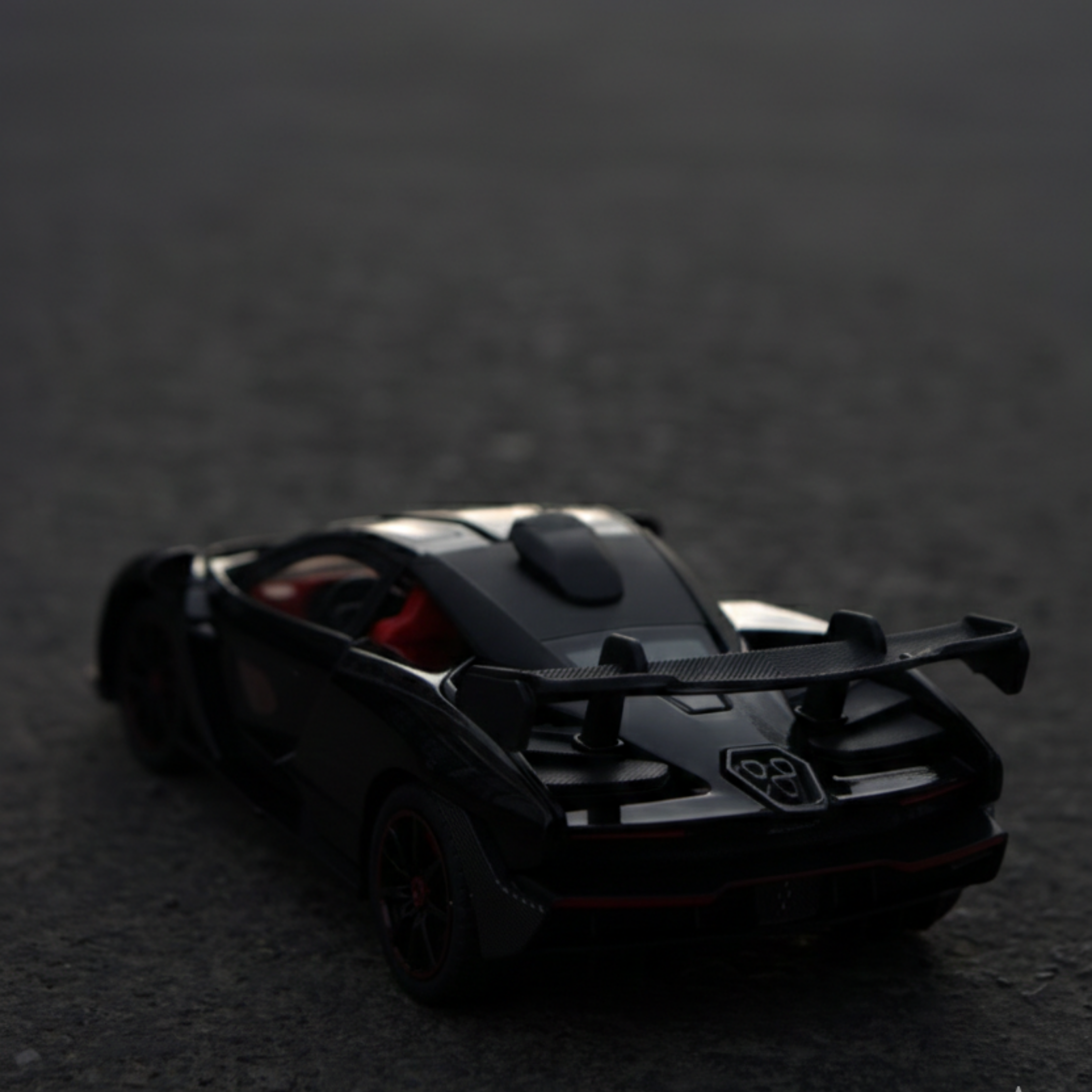 Black toy car on a dark surface