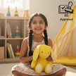 Child holding Claptales yellow bunny soft toy indoors during playtime