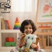 Child holding a plush elephant toy in a room with books and a colorful tower.