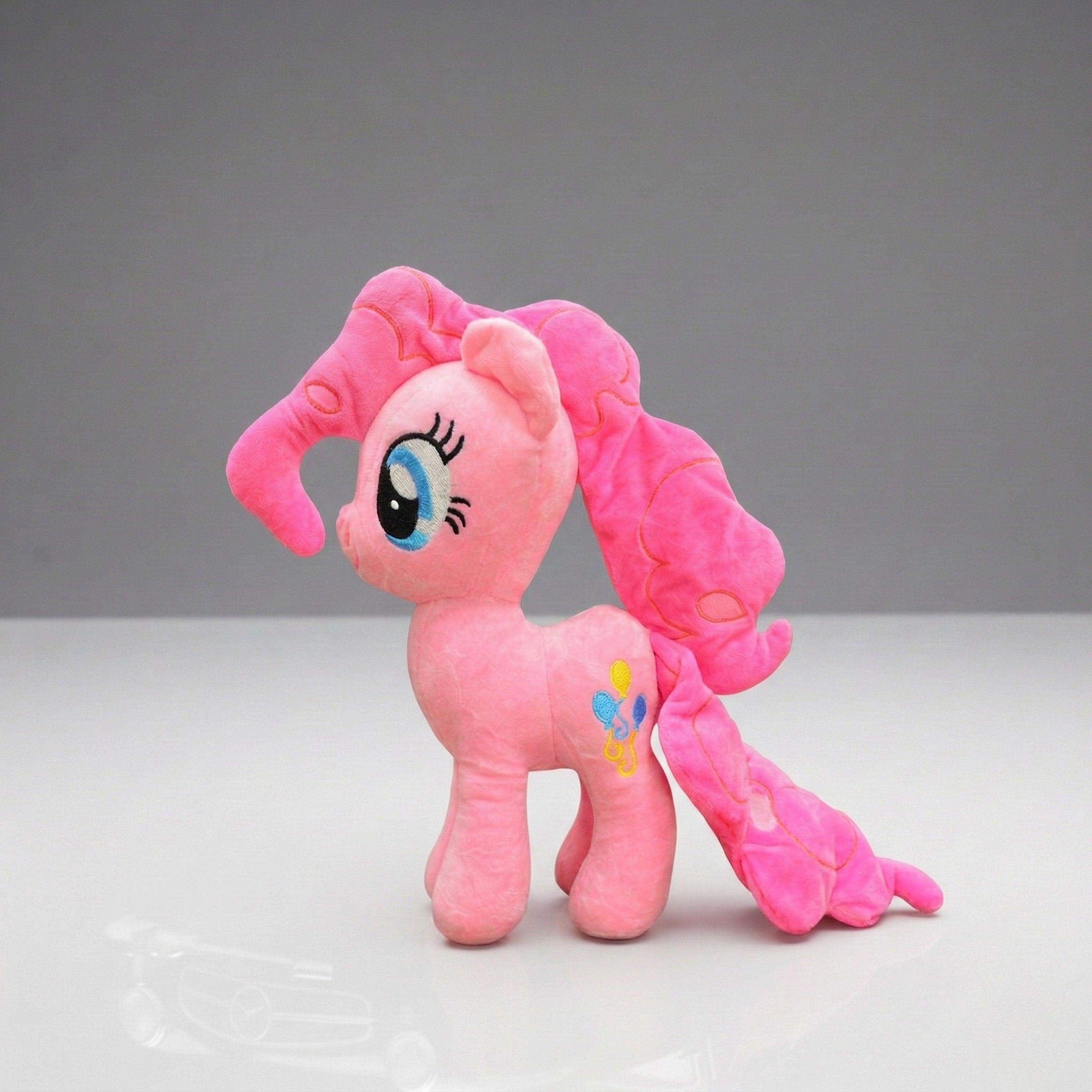 Pink plush toy with a rainbow on a gray background