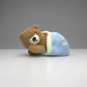 Plush bear toy in a blue outfit on a gray background