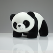 Plush panda toy on a reflective surface with a gray background