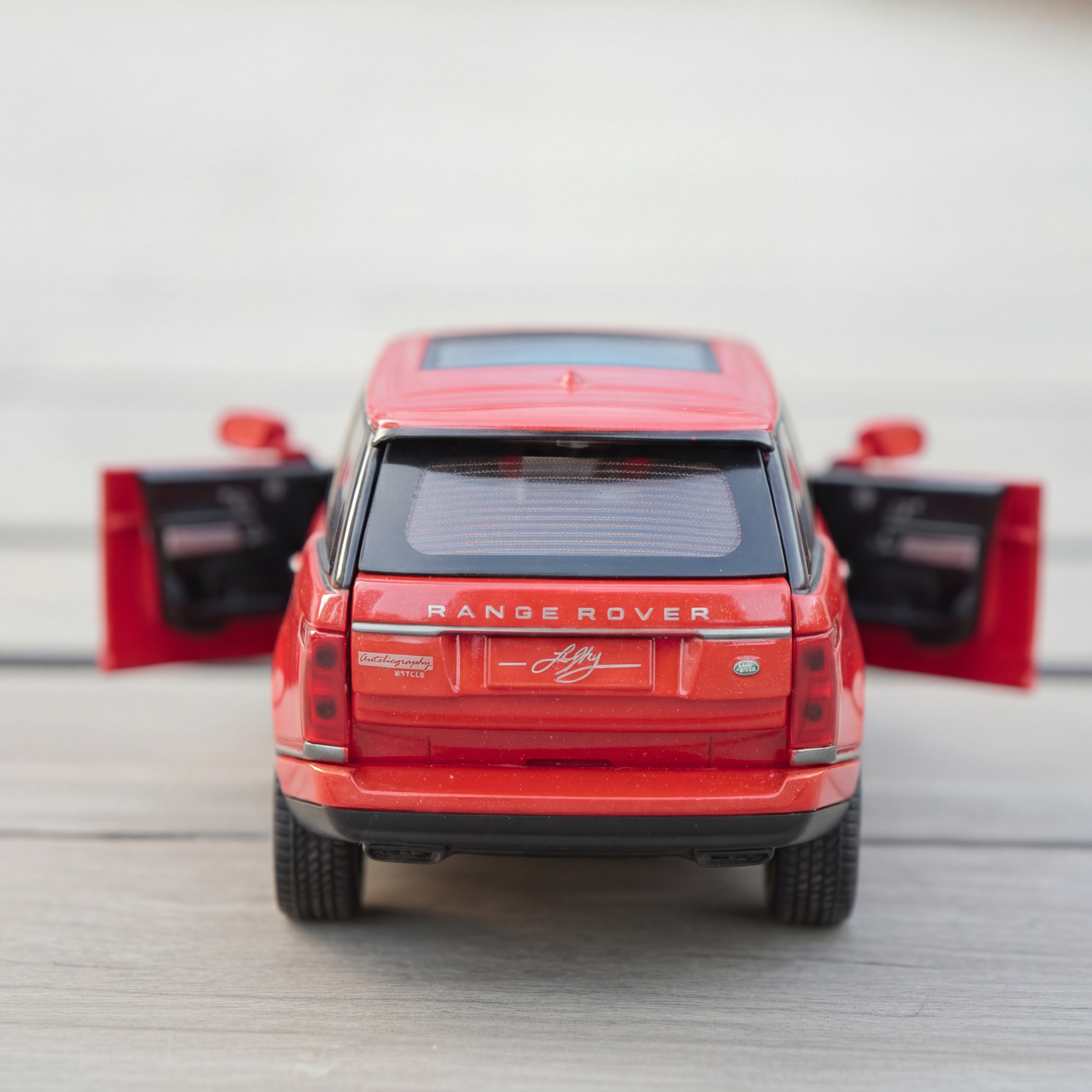 Red model Range Rover with open doors on a light gray background