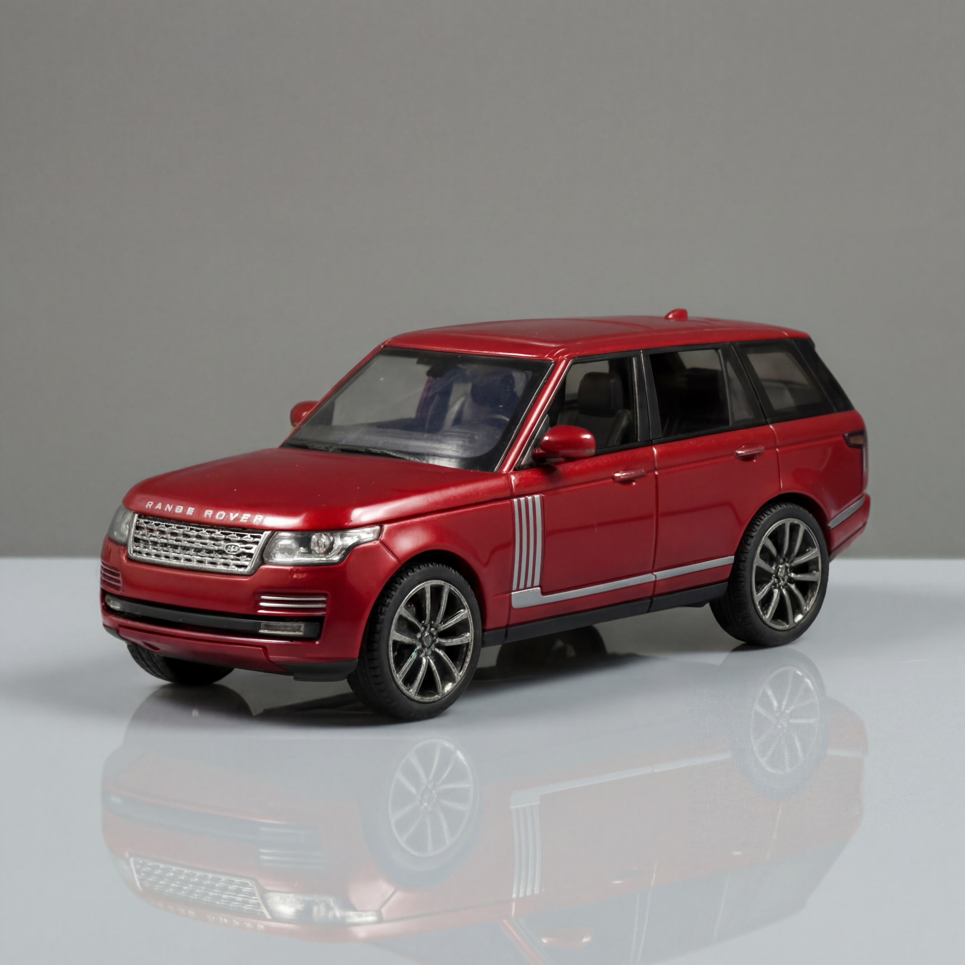 Red model car on a reflective surface with a gray background